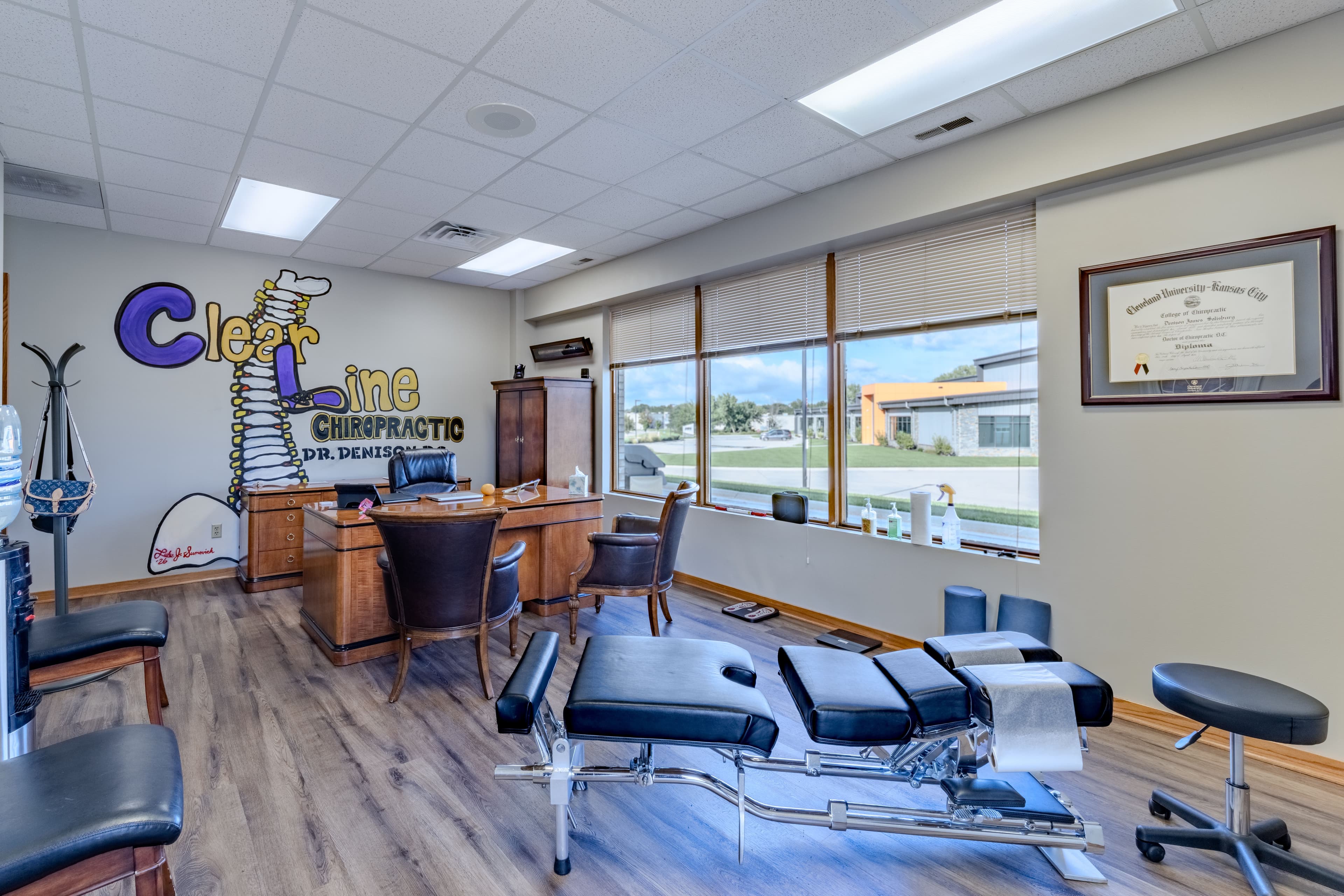 ClearLine Chiropractic treatment room with adjusting table and branded wall mural