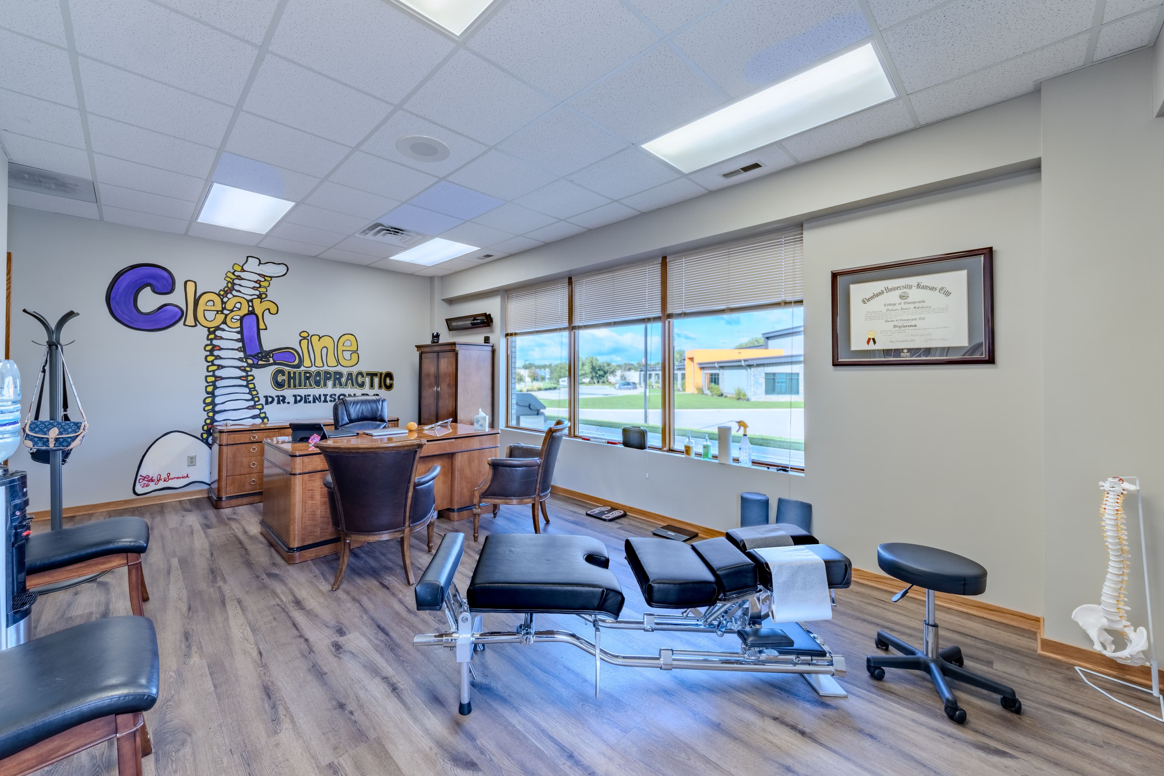 Treatment room at ClearLine Chiropractic with adjusting table and spine model